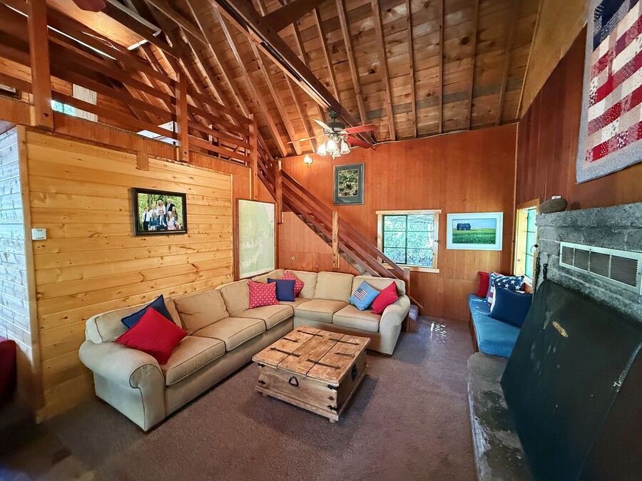 Wood-paneled living room with a sectional sofa, fireplace and a flag quilt on the wall